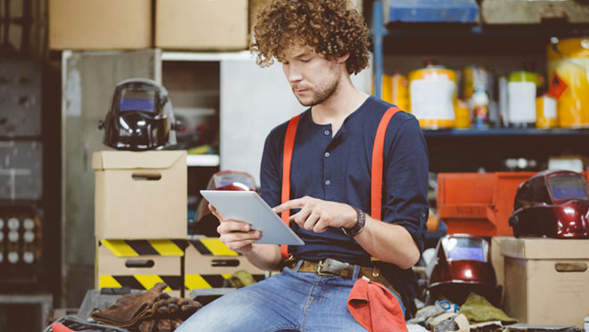 Hombre buscando en una tablet dentro de un almacén
